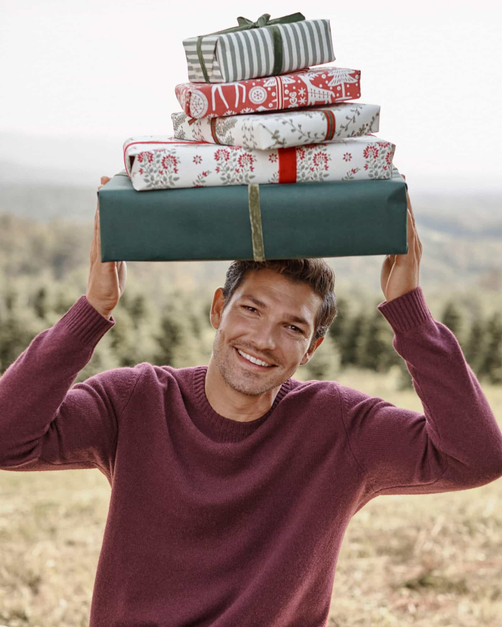 A man carrying a stack of gifts. Shop gifts for men.