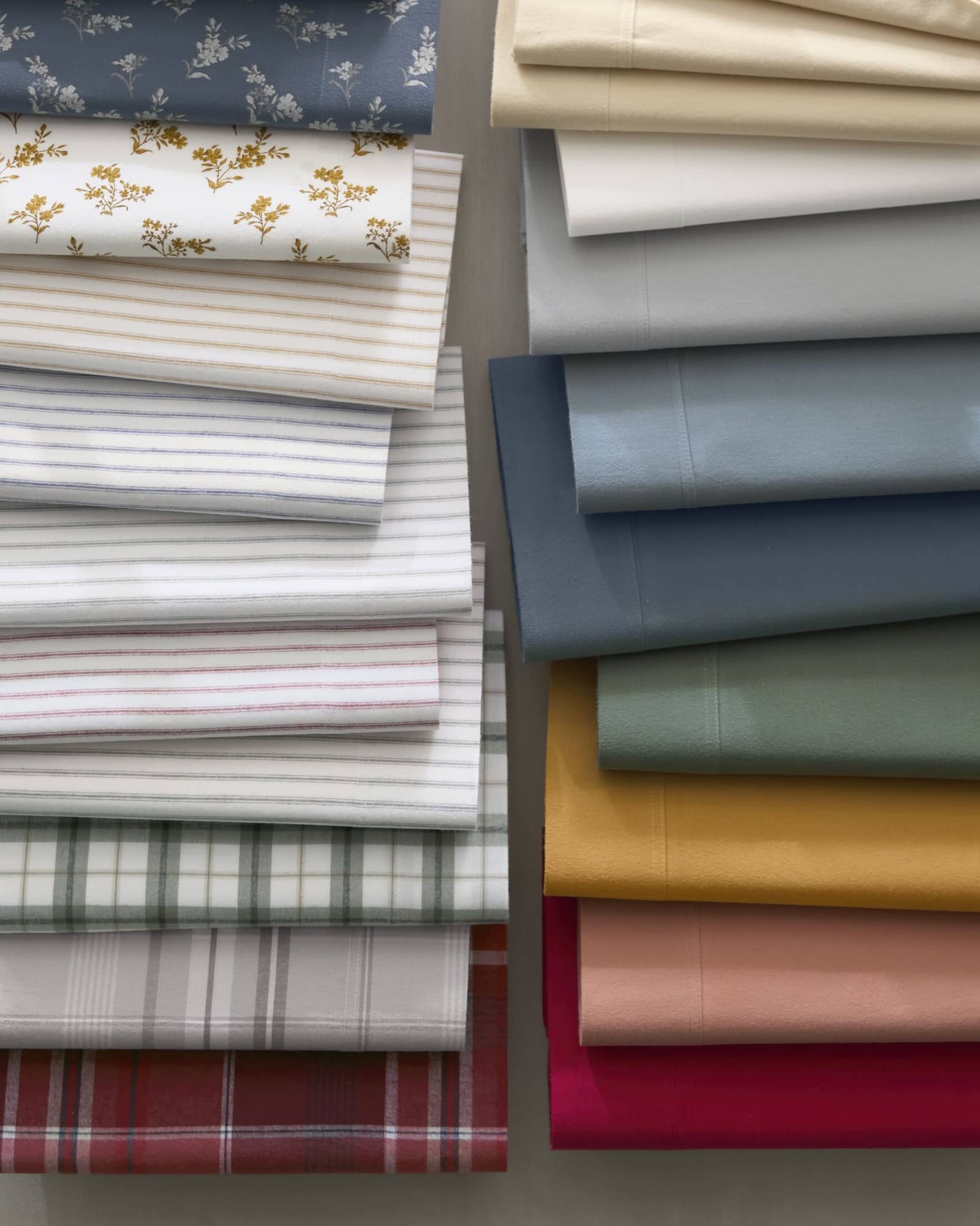 Two rows of overlapping folded flannel sheets in solid colors and prints.